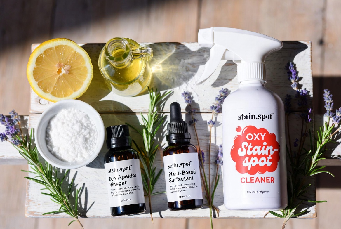Natural ingredients flat lay showing lemons, vinegar, baking soda, essential oils and a Stain.spot bottle